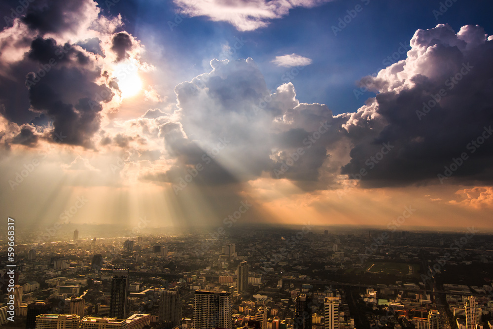 Fototapeta premium Rays of light shining through dark clouds in Bangkok, Thailand