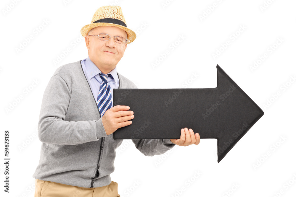 Smiling senior gentleman holding a big black arrow pointing to t Smiling senior gentleman holding a big black arrow pointing to t