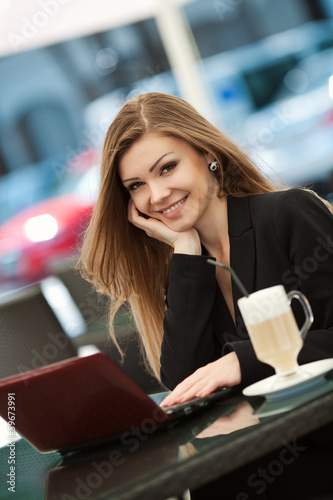 portrait of a young woman in a cafe with a laptop