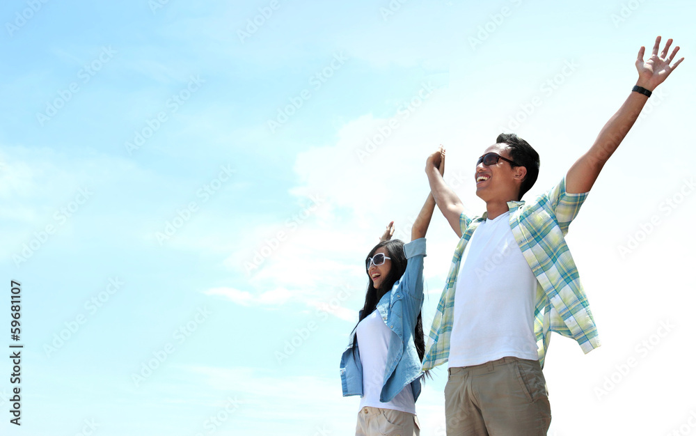 Asian Young couple standing and raised their hands to the sky