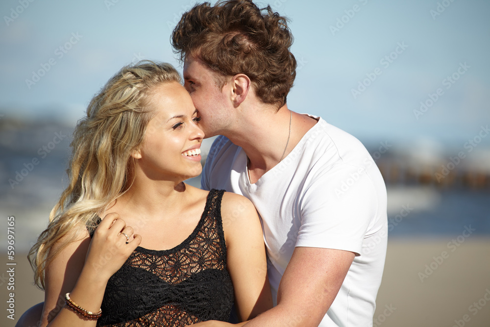 Young beautiful couple in love sitting near the water