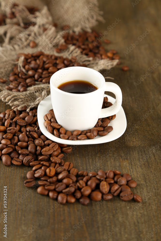 Obraz premium Cup of coffee and coffee beans on wooden background