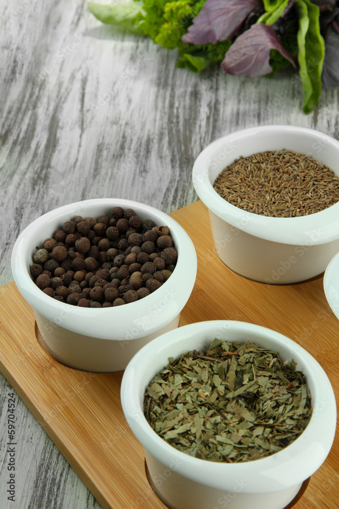Assortment of spices in white bowls, on wooden background Assortment of spices in white bowls, on wooden background