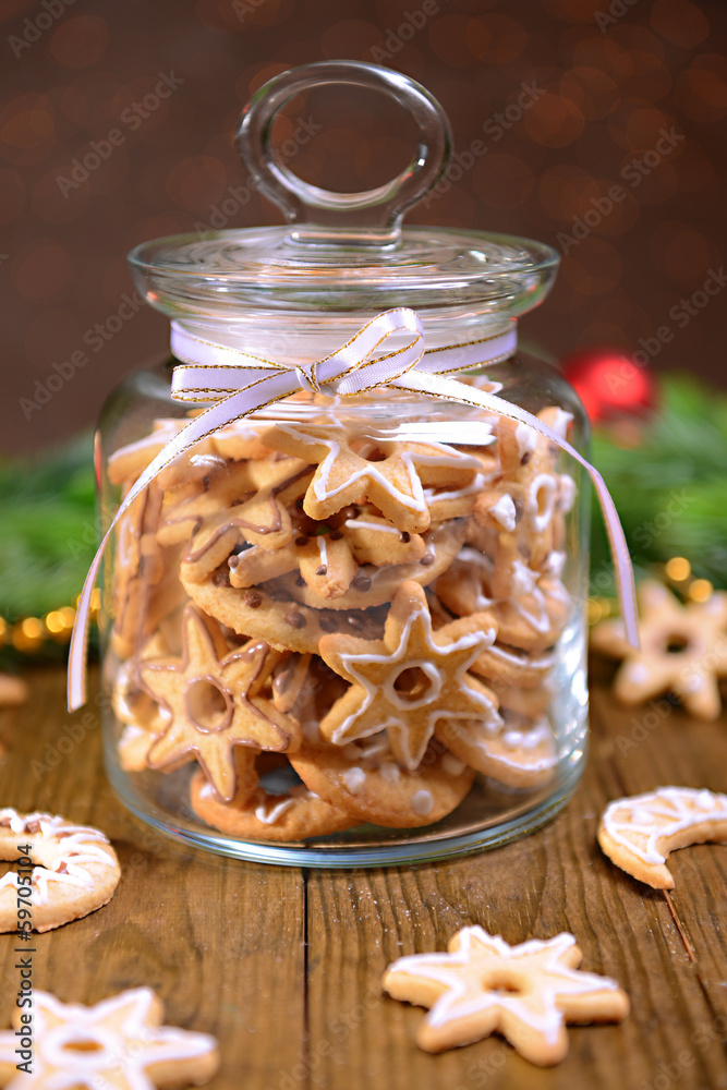Fototapeta premium Delicious Christmas cookies in jar on table on brown background