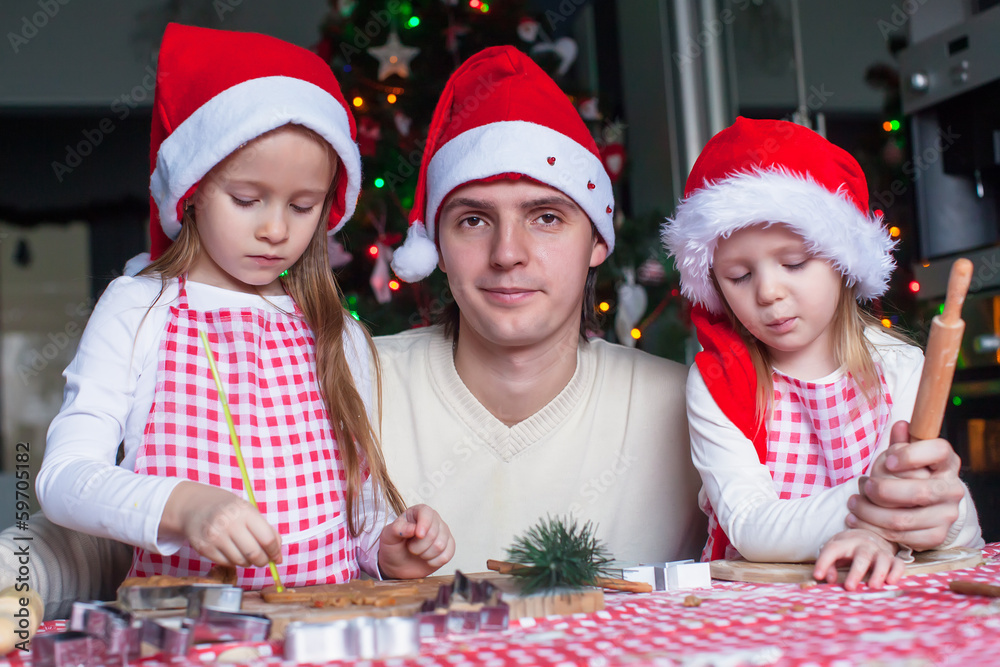 Young dad with little daughters in Santa hat bake Christmas Young dad with little daughters in Santa hat bake Christmas