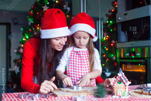 Little adorable girl and young mother baking Christmas