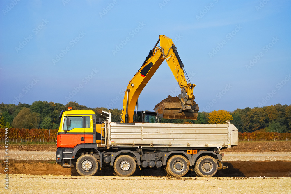 Bagger schaufelt Erde auf Ladefläche von LKW Bagger schaufelt Erde auf Ladefläche von LKW