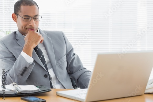 Smiling businessman looking at laptop in office