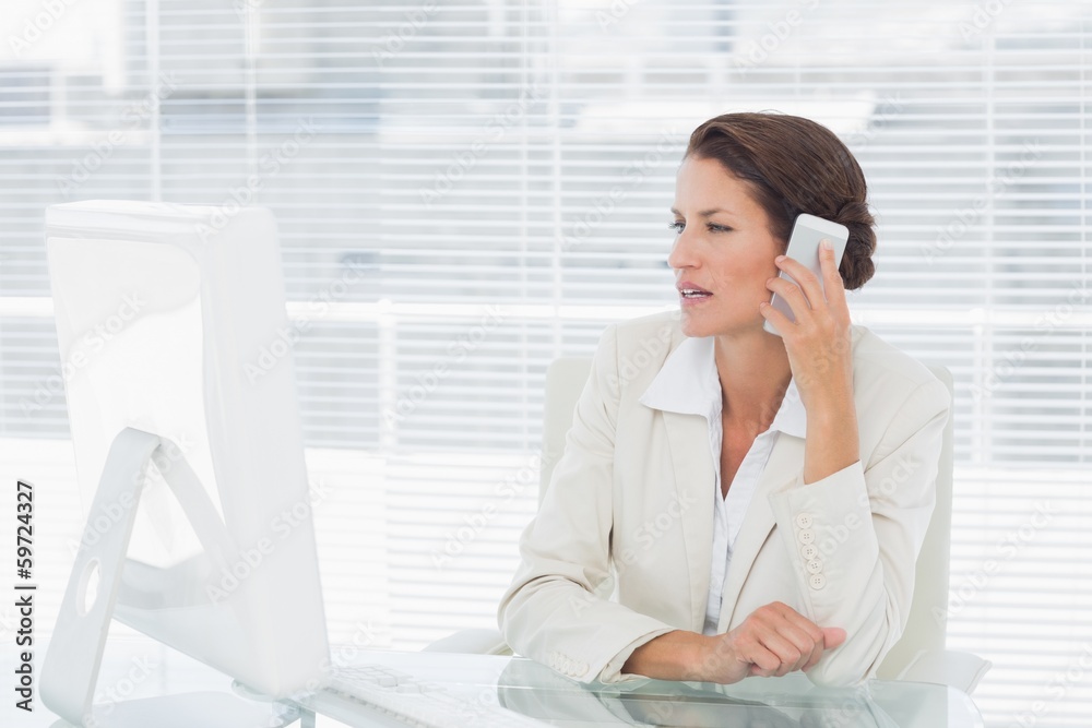 Businesswoman using computer and cellphone at desk Businesswoman using computer and cellphone at desk