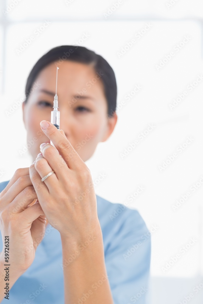 Serious female doctor holding an injection Serious female doctor holding an injection