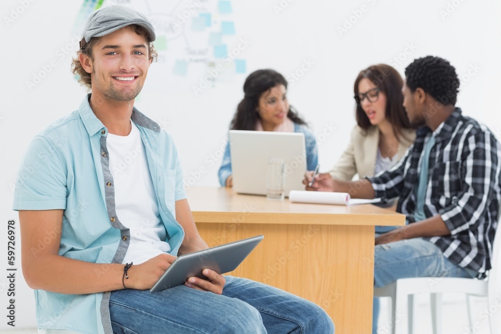 Man using digital tablet with colleagues behind in office Man using digital tablet with colleagues behind in office