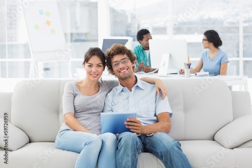 Couple using digital tablet with colleagues at creative office