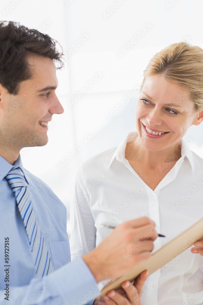 Happy business team working from clipboard together Happy business team working from clipboard together