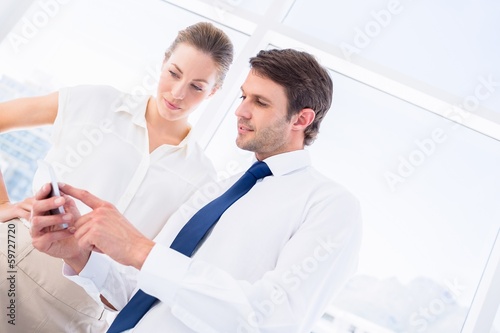 Smartly dressed colleagues looking at mobile phone
