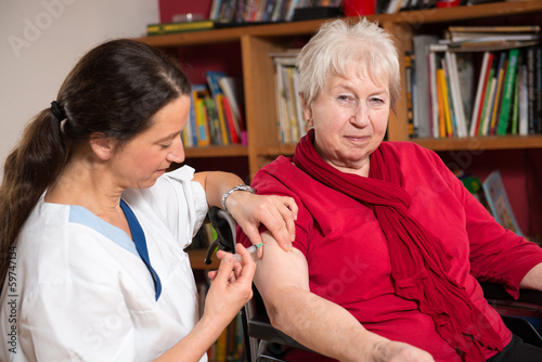 Seniorin im Rollstuhl bekommt eine Injektion