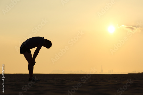Silhouette of an exhausted sportsman at sunset