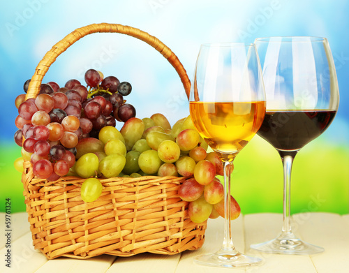 Ripe grapes in wicker basket, and two glasses of wine,