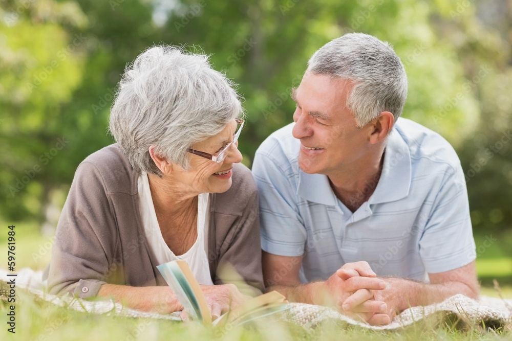Smiling relaxed senior couple lying in park Smiling relaxed senior couple lying in park