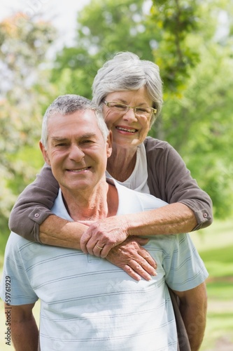 Senior woman embracing man from behind at park