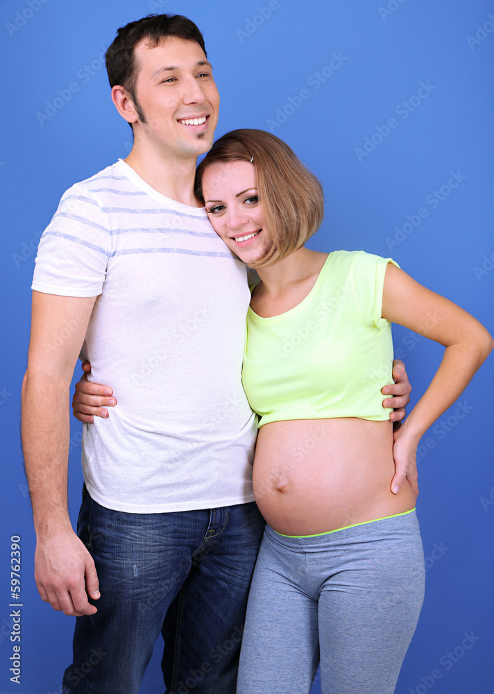 Young pregnant woman with her husband on blue background Young pregnant woman with her husband on blue background