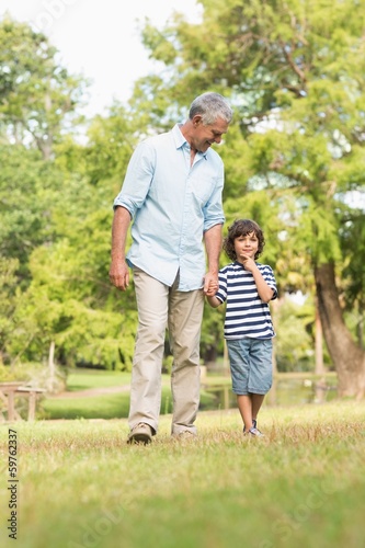 Grandfather and son walking on grass in park