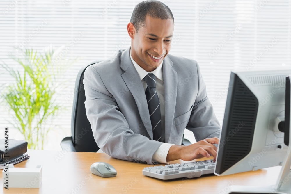 Smiling businessman using computer at office Smiling businessman using computer at office