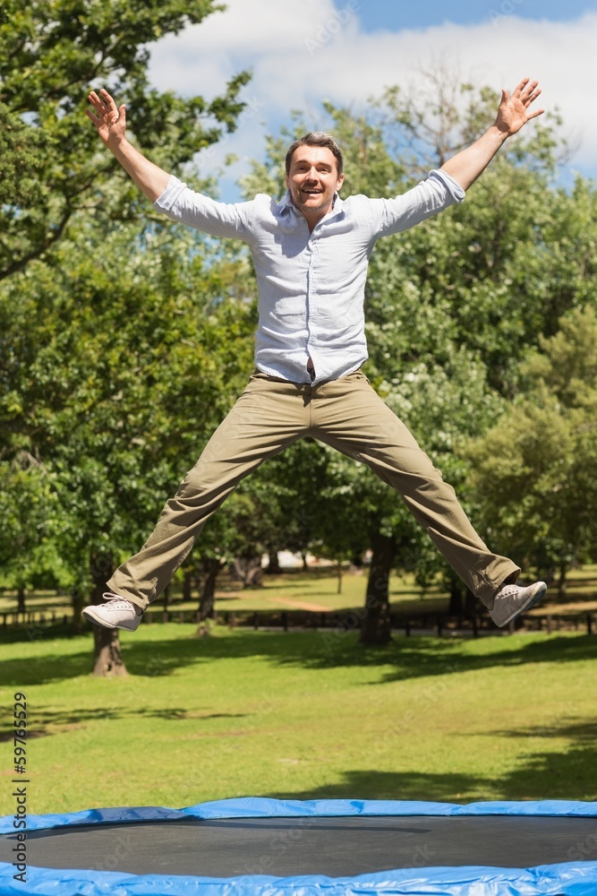 Happy man jumping high on trampoline in park Happy man jumping high on trampoline in park