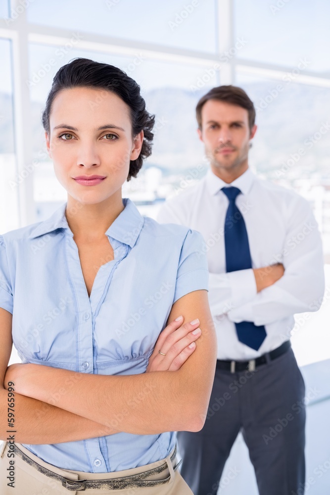 Serious businesswoman with male colleague in background Serious businesswoman with male colleague in background