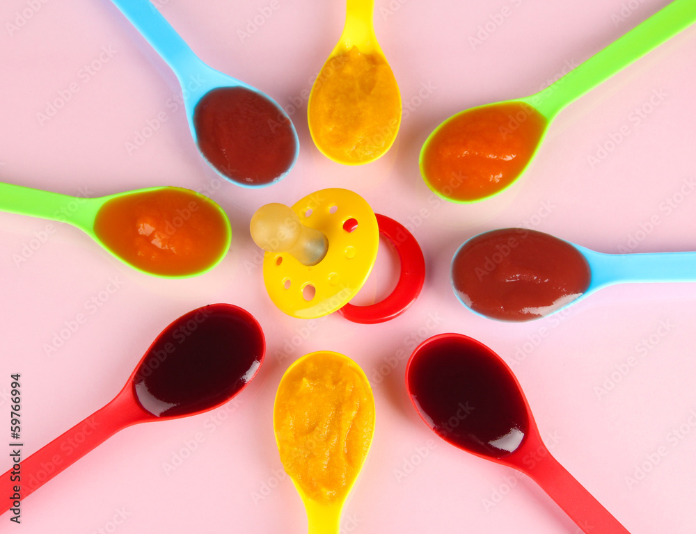 Baby puree in spoons with nipple on pink background Baby puree in spoons with nipple on pink background
