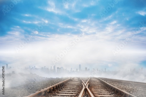 Train tracks leading to city on the horizon