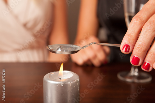 Damenhand hält Löffel für Bleigießen über Kerze
