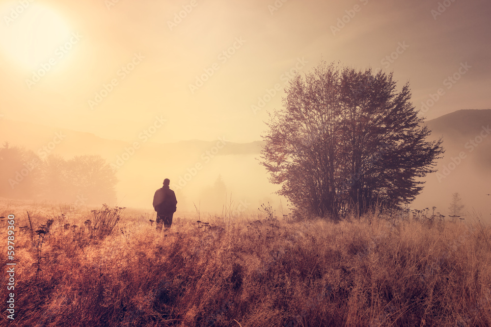 Lonely person in the morning mist. Landscape composition.