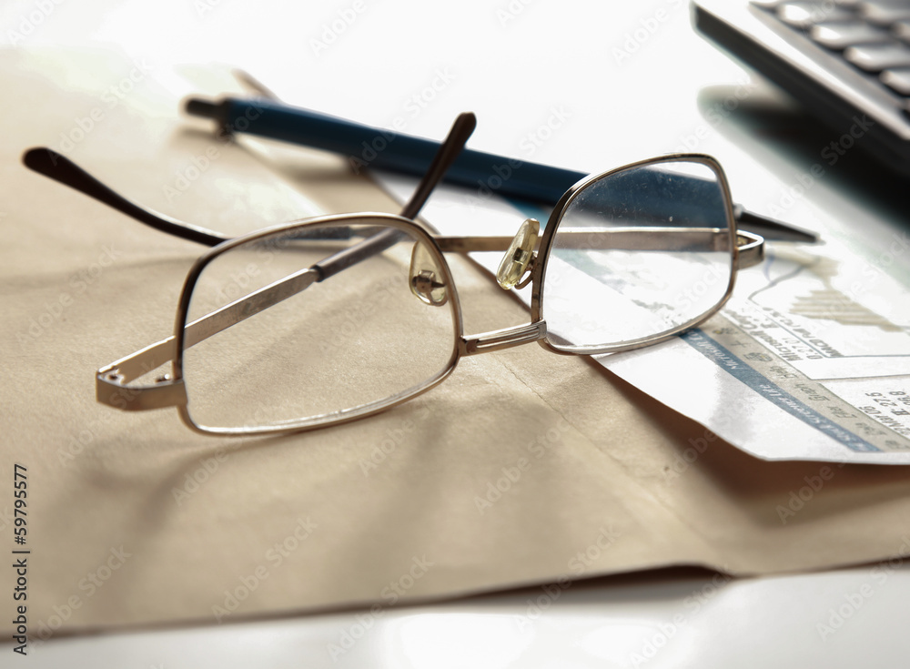 Financial charts, a pen and glasses.