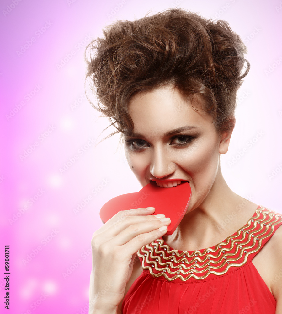 girl in red dress eats heart. Concept of Valentine's Day girl in red dress eats heart. Concept of Valentine's Day
