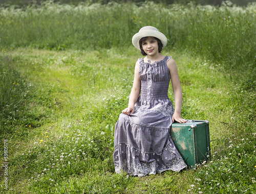 The girl in a hat with a suitcase in the field