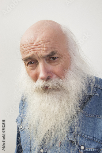 Portrait of suspicious senior man over gray background