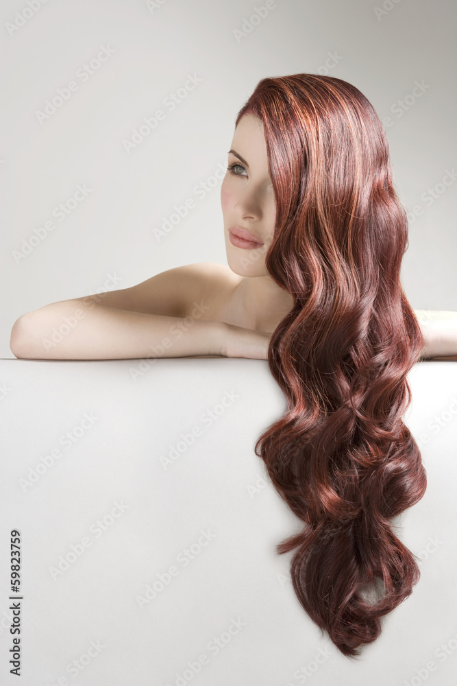Fototapeta premium Thoughtful woman with long red dyed hair against gray background