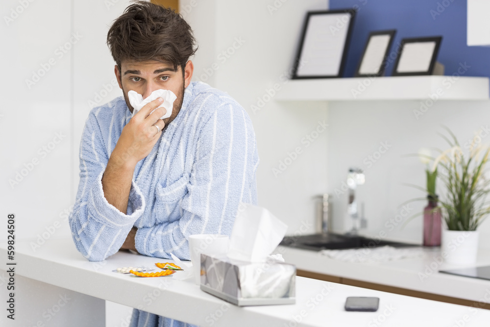 Young ill man blowing nose in tissue paper Young ill man blowing nose in tissue paper