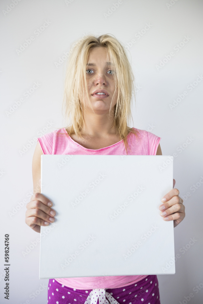 Portrait of woman suffering from cold holding blank placard against gray background Portrait of woman suffering from cold holding blank placard against gray background