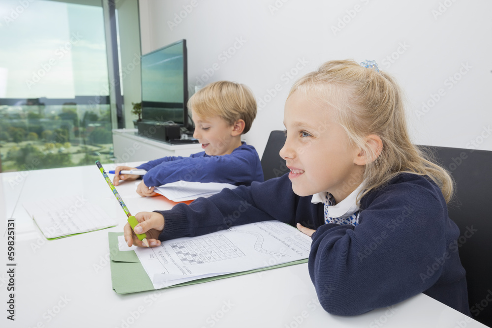 Brother and sister doing homework at table in house Brother and sister doing homework at table in house