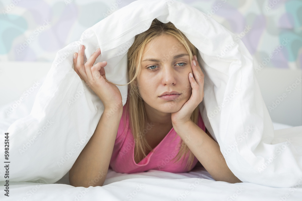 Thoughtful ill woman covered with quilt in bed Thoughtful ill woman covered with quilt in bed