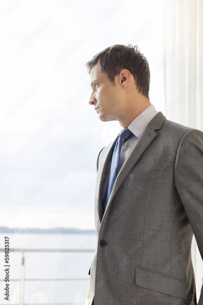 Pensive businessman standing by glass door in hotel Pensive businessman standing by glass door in hotel