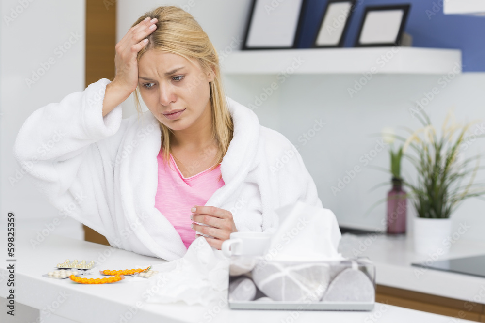 Young woman suffering from cold in kitchen Young woman suffering from cold in kitchen