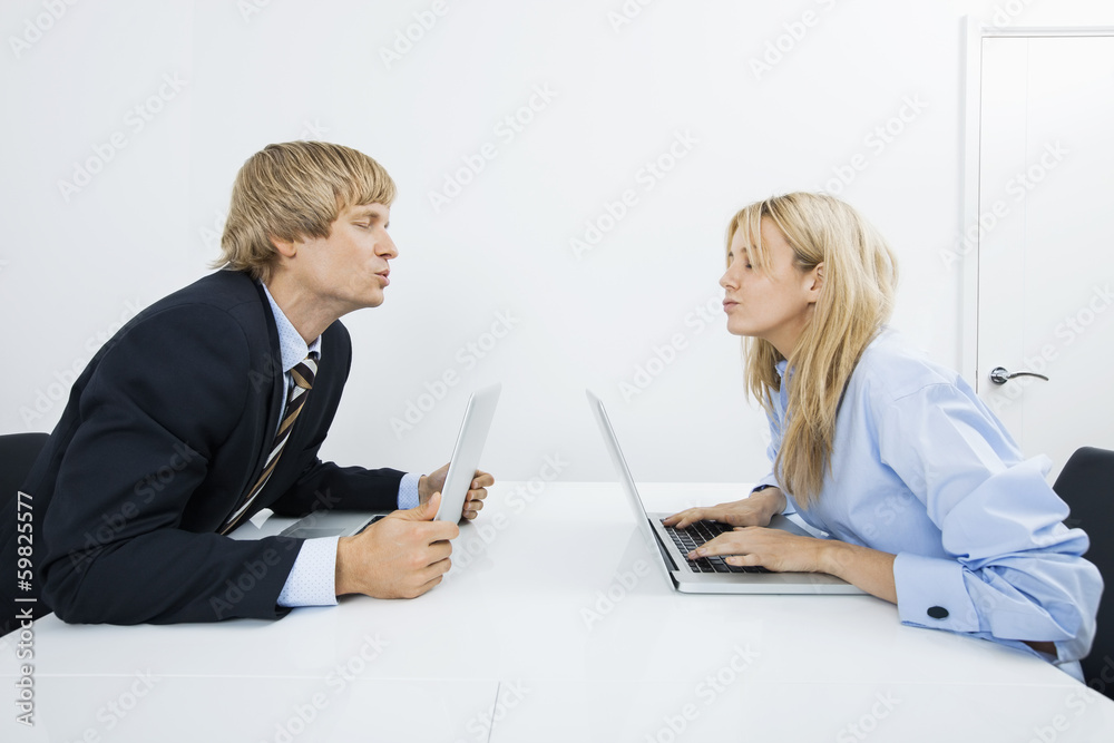 Side view of business couple kissing in office