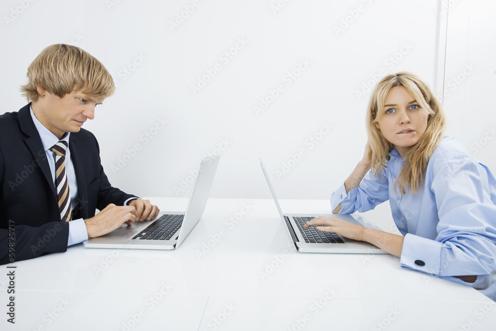Portrait of businesswoman with coworker using laptop in office Portrait of businesswoman with coworker using laptop in office