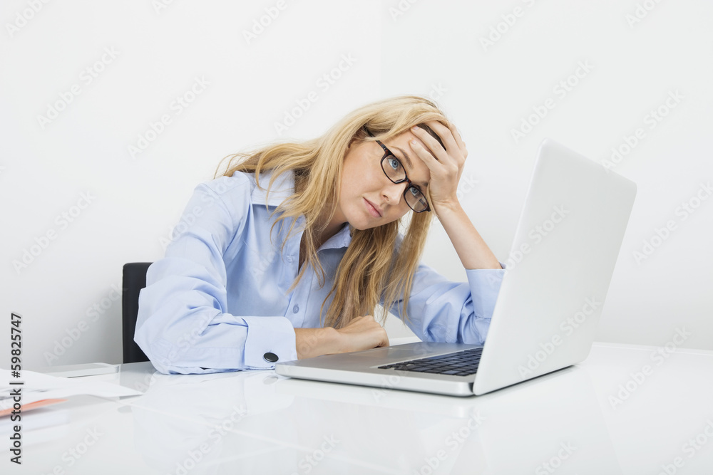 Frustrated businesswoman looking at laptop in office Frustrated businesswoman looking at laptop in office