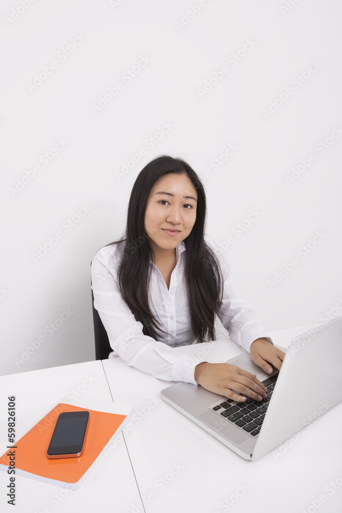 Portrait of confident businesswoman working on laptop in office Portrait of confident businesswoman working on laptop in office