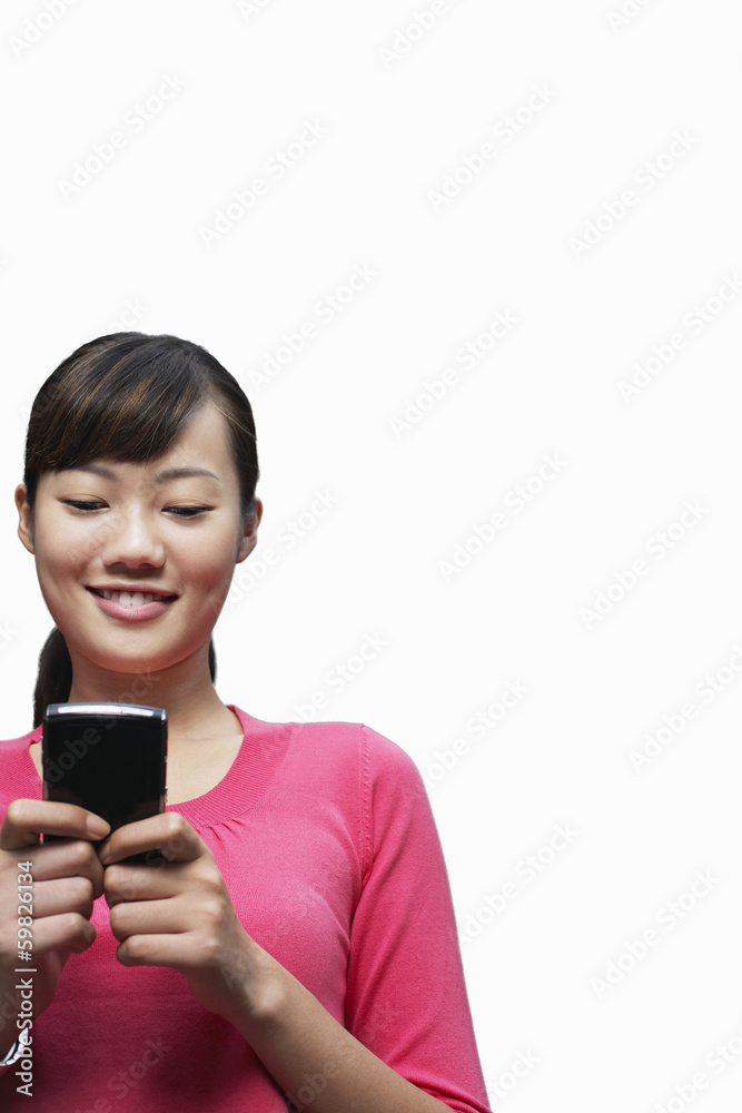 Young woman text messaging on cell phone against white background Young woman text messaging on cell phone against white background