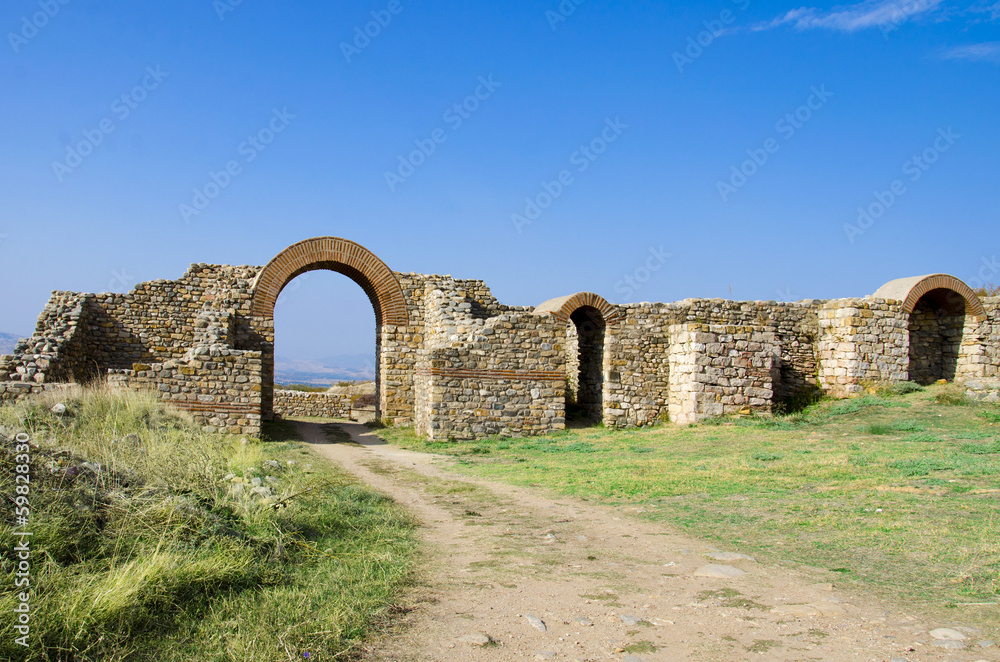 ancient town ruins and path through arced stone gate