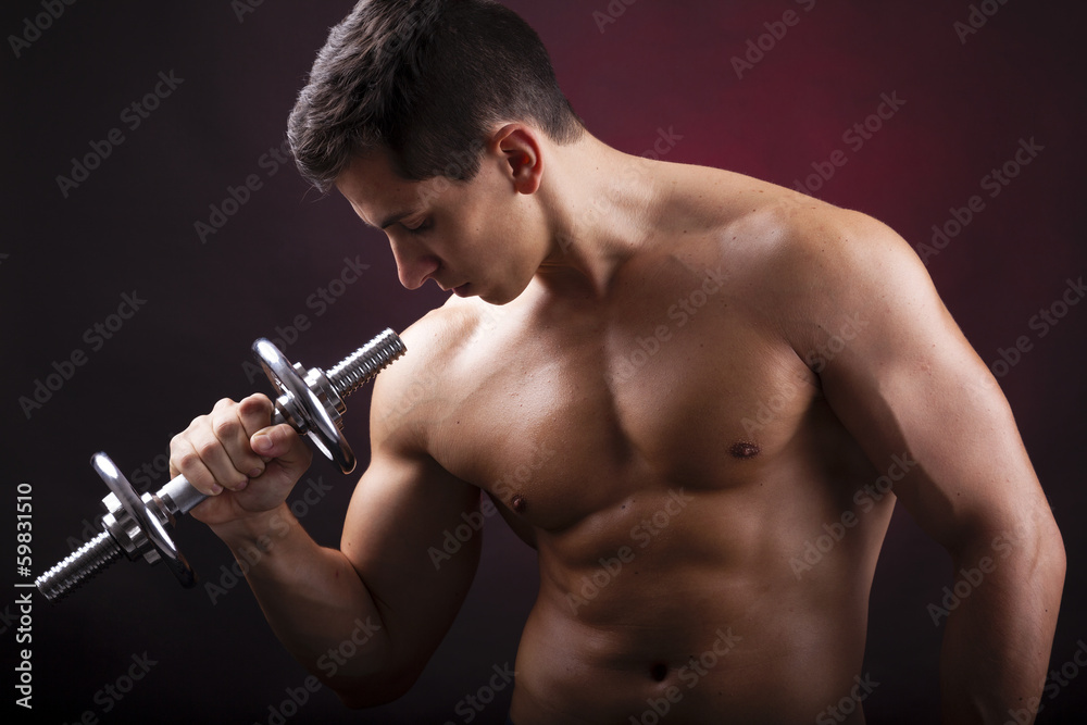 Image of a muscular young man lifting weights on black backgroun